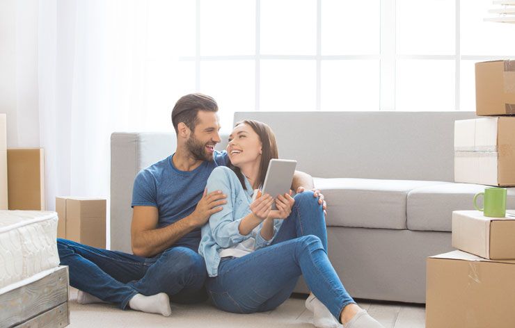 Man and Woman Sitting on Floor against Couch with Boxes Man and Woman Sitting on Floor against Couch with Boxes